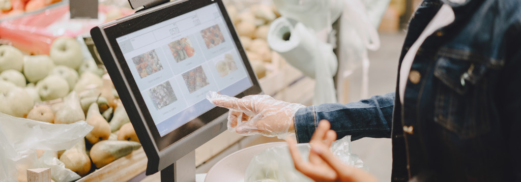 Pessoa utilizando um terminal de ponto de venda com tela touch em um supermercado, representando o uso de PDV inteligente para agilizar o atendimento e a gestão das vendas no varejo.