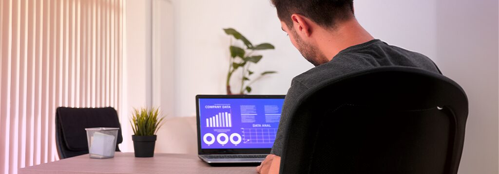 Homem analisando gráficos de desempenho em um notebook, representando gestão de dados em tempo real com ERP